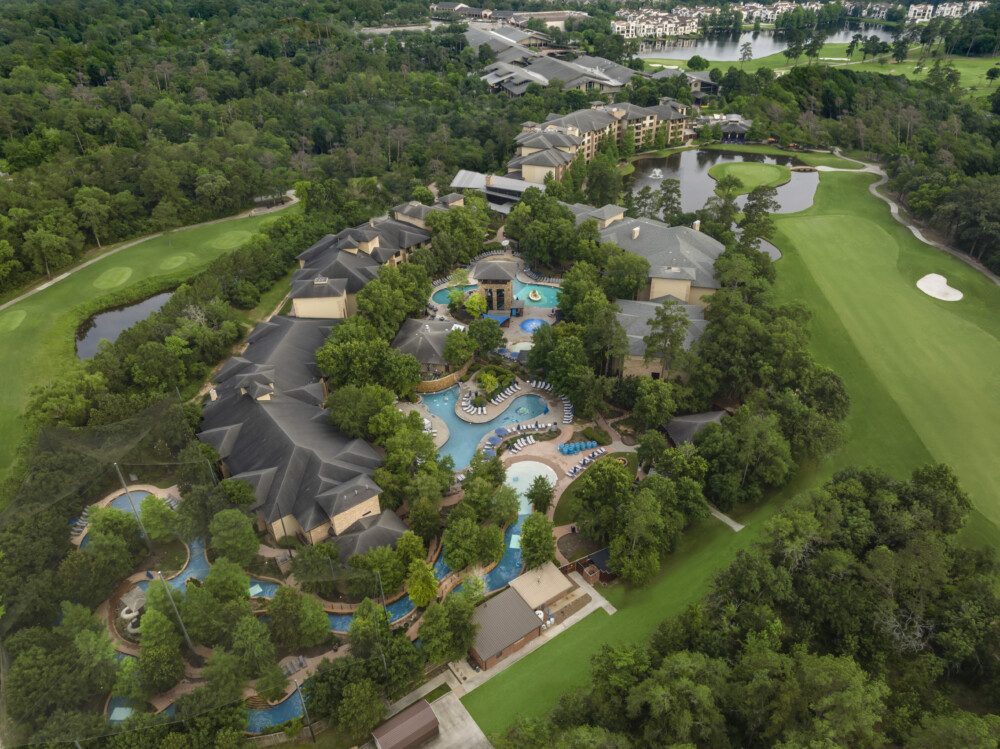 Aerial shot of the resort showing the buildings, pools, lazy river, golf course and surrounding trees.